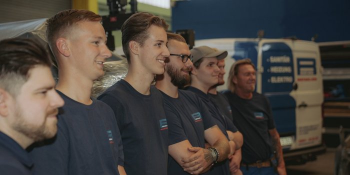 Die Gruppe von Männern zeigt Freude und Zusammenhalt, während sie in einer professionellen Umgebung posieren.