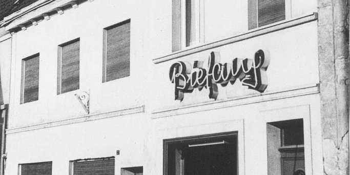 Ein historisches Gebäude mit einem auffälligen, beleuchteten Schild, das den Namen 'Befall' zeigt, in Schwarz-Weiß.