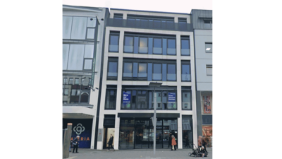 Ein modernes Gebäude mit großen Fenstern und einem klaren, minimalistischen Design, das in einer urbanen Umgebung steht.