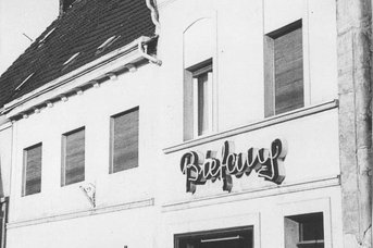 Ein historisches Gebäude mit einem auffälligen, beleuchteten Schriftzug 'Befang' an der Fassade, umgeben von geschlossenen Fenstern.